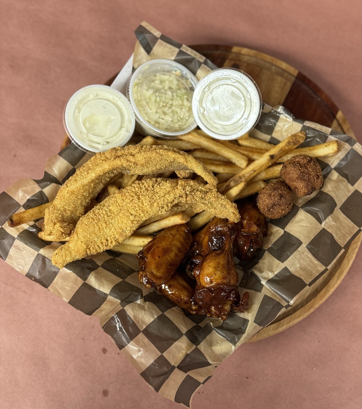 Wing and fish basket with catfish, BBQ wings, fries, slaw, and hush puppies
